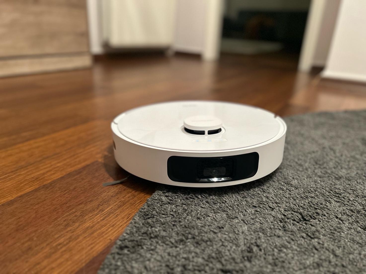 A white robot vacuum on a wood floor AI-generated content may be incorrect.